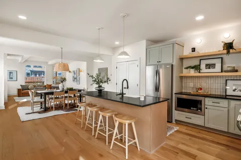 a kitchen with stainless steel appliances kitchen island granite countertop a table chairs and a refrigerator