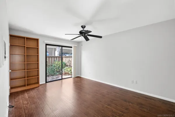 a view of empty room with wooden floor and fan