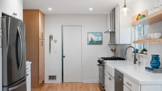 a kitchen with stainless steel appliances a refrigerator a sink and white cabinets