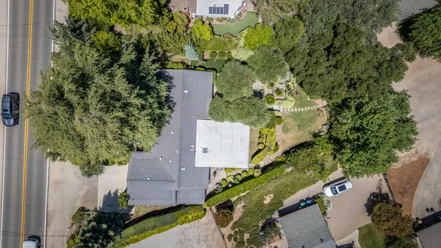 an aerial view of a house with a yard and trees all around