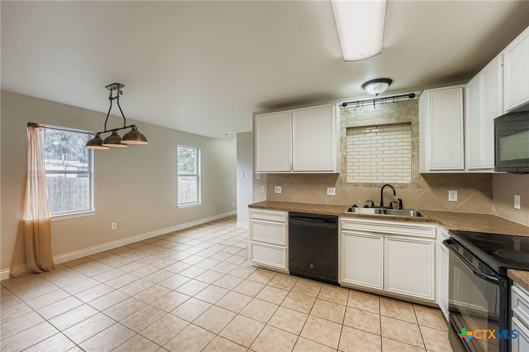 304 South Main Street Elgin, TX 78621 - Photo 12 of 25 Kitchen with decorative backsplash, black appliances, and white cabinetry