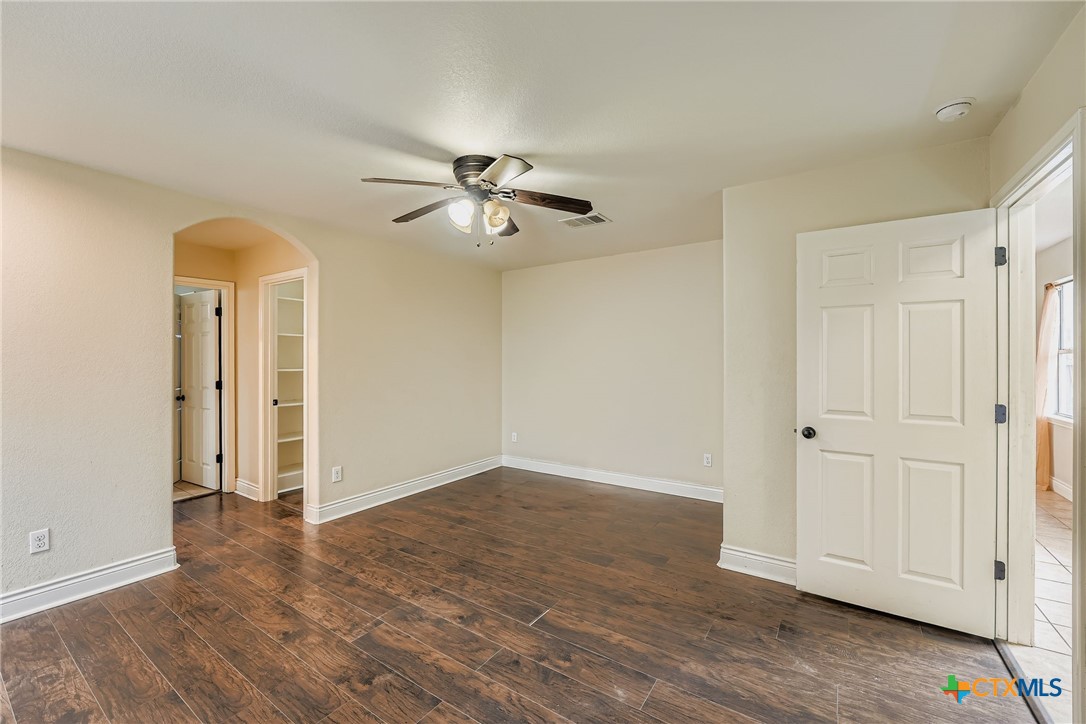 304 South Main Street Elgin, TX 78621 - Photo 16 of 25 Large bedroom with arched walkways, dark wood flooring, and ceiling fan