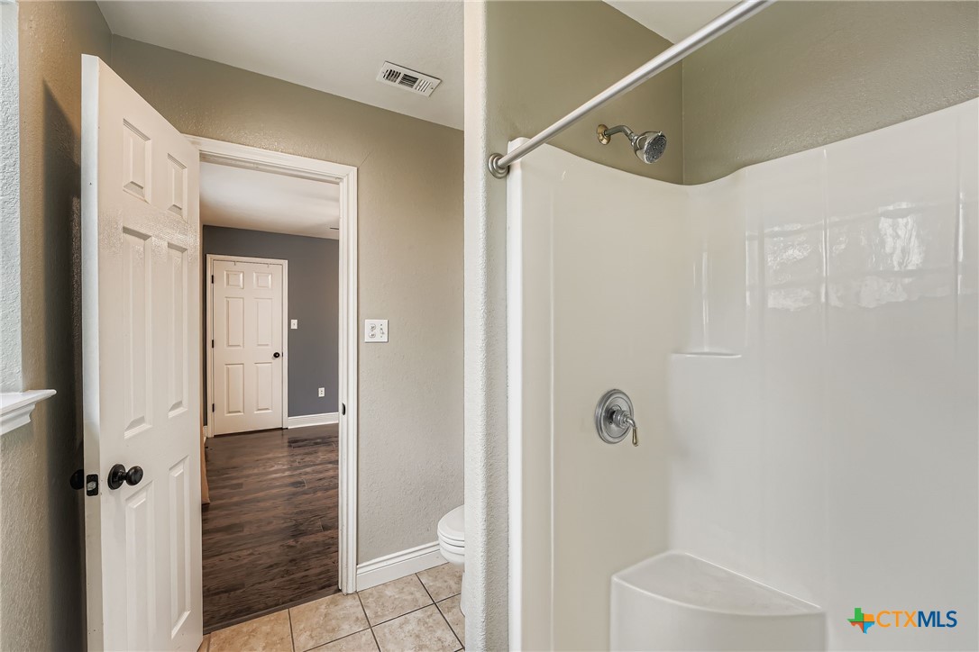 304 South Main Street Elgin, TX 78621 - Photo 18 of 25 Bathroom with a stall shower, a textured wall, and light tile patterned floors