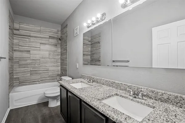 a bathroom with a granite countertop sink a toilet a mirror and shower