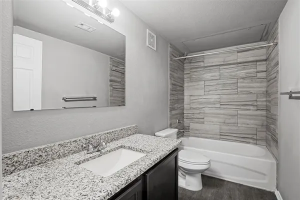 a bathroom with a granite countertop sink toilet and shower
