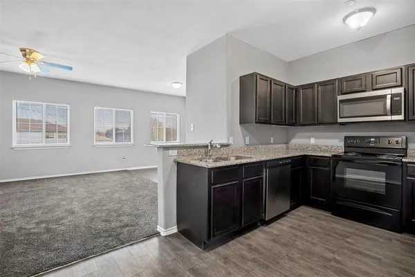 a kitchen with stainless steel appliances granite countertop a stove a sink and a microwave