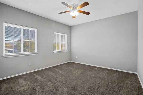 an empty room with windows and fan