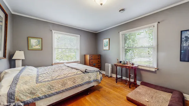 a bedroom with a bed a table and windows