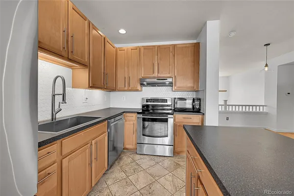 a kitchen with stainless steel appliances granite countertop a stove a sink and a refrigerator