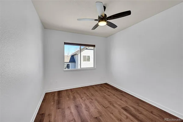 an empty room with a window and a fan