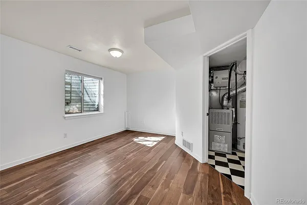 an empty room with wooden floor closet and windows
