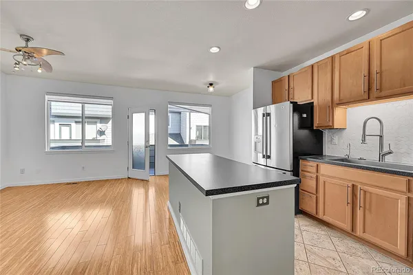 a kitchen with stainless steel appliances granite countertop a refrigerator a sink dishwasher a stove with wooden cabinets and floors