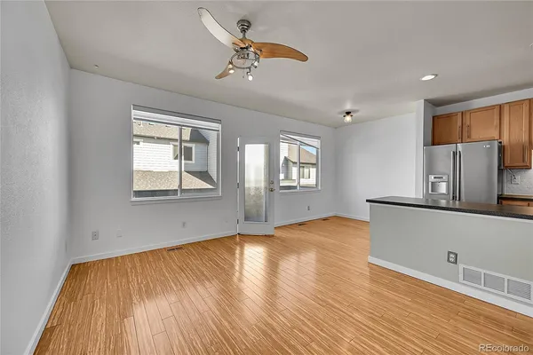 a view of empty room with wooden floor and fan