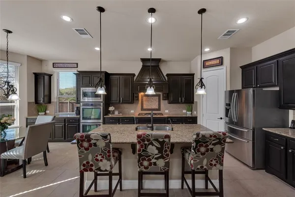 a kitchen with stainless steel appliances kitchen island granite countertop a dining table chairs and stove