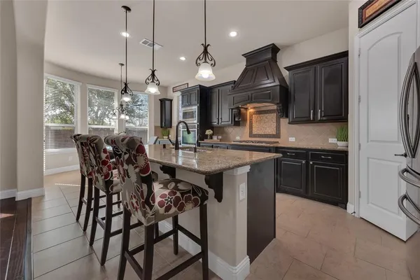 a kitchen with stainless steel appliances granite countertop a kitchen island a stove a table and chairs