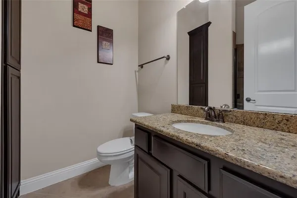 a bathroom with a granite countertop sink a toilet and mirror