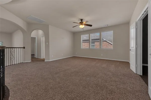 an empty room with windows and ceiling fan