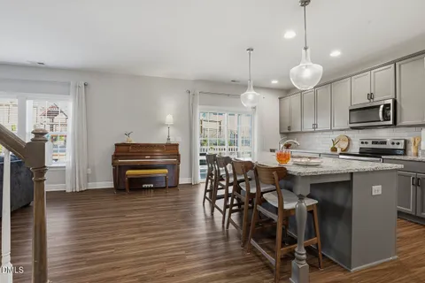 a kitchen with stainless steel appliances granite countertop wooden floors and a view of living room