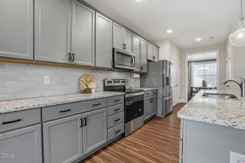 a kitchen with stainless steel appliances granite countertop a stove a kitchen island a dining table and chairs