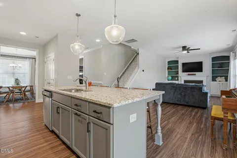 a kitchen with stainless steel appliances granite countertop a stove a refrigerator a kitchen island a dining table and chairs with wooden floor