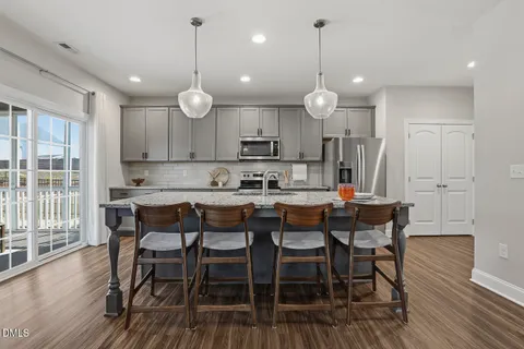 a kitchen with stainless steel appliances granite countertop a sink a stove and a wooden floors