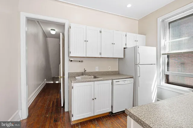 a kitchen with a refrigerator a stove and white cabinets