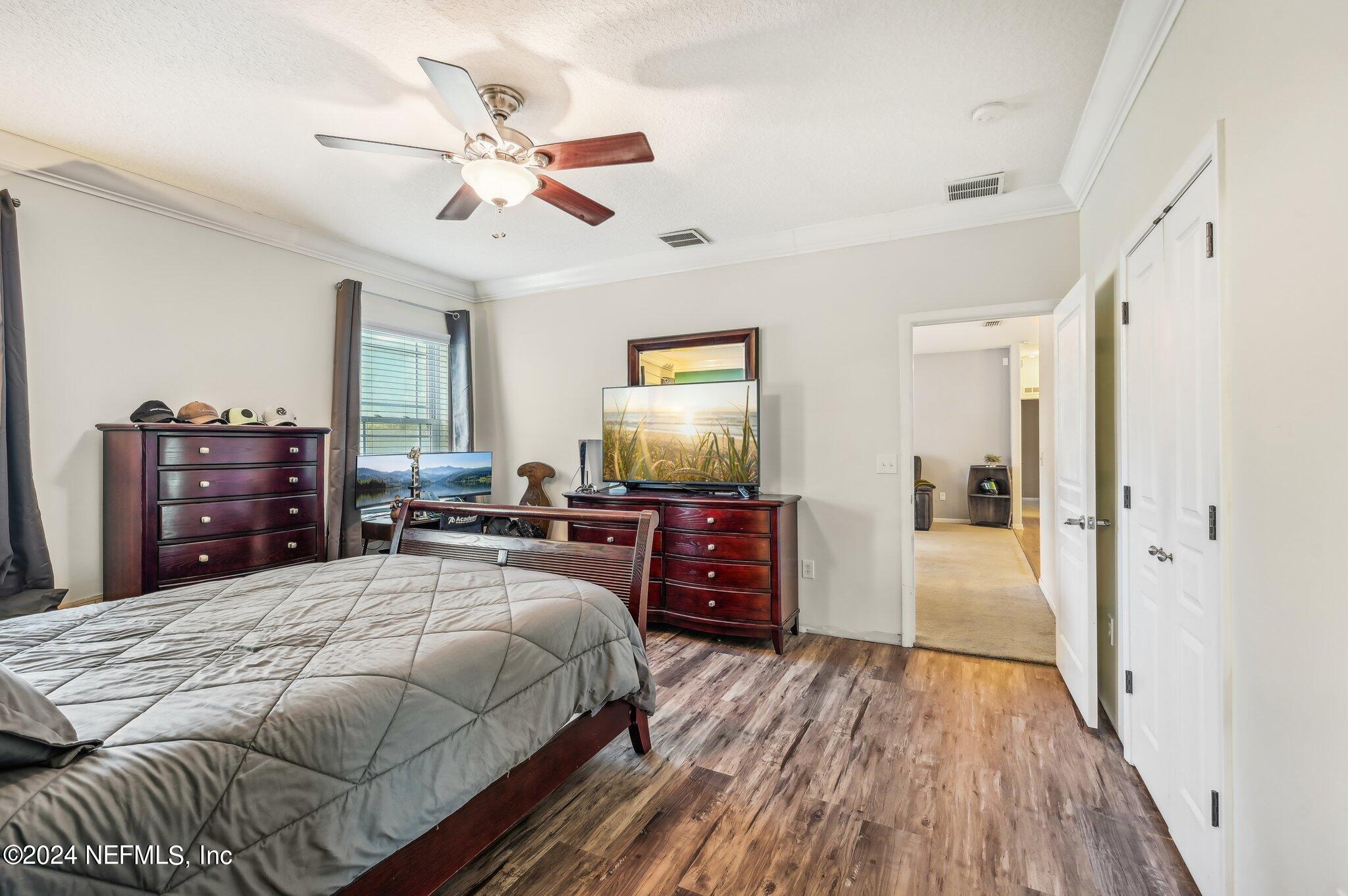 4253 Dalry Drive Jacksonville, FL 32246 - Photo 15 of 40 a bedroom with a bed and dresser with wooden floor