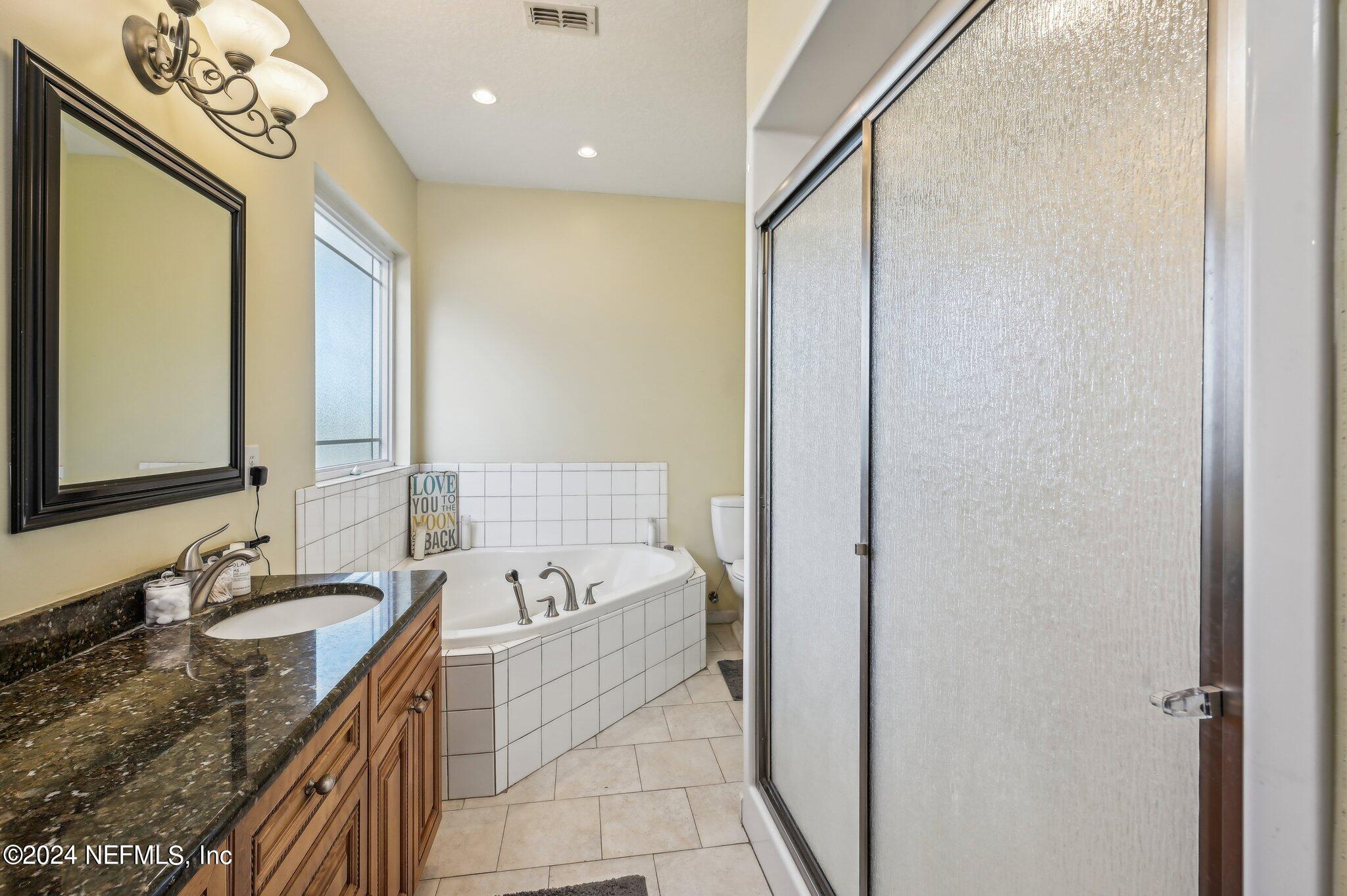 4253 Dalry Drive Jacksonville, FL 32246 - Photo 17 of 40 a bathroom with a granite countertop sink a mirror and a bathtub