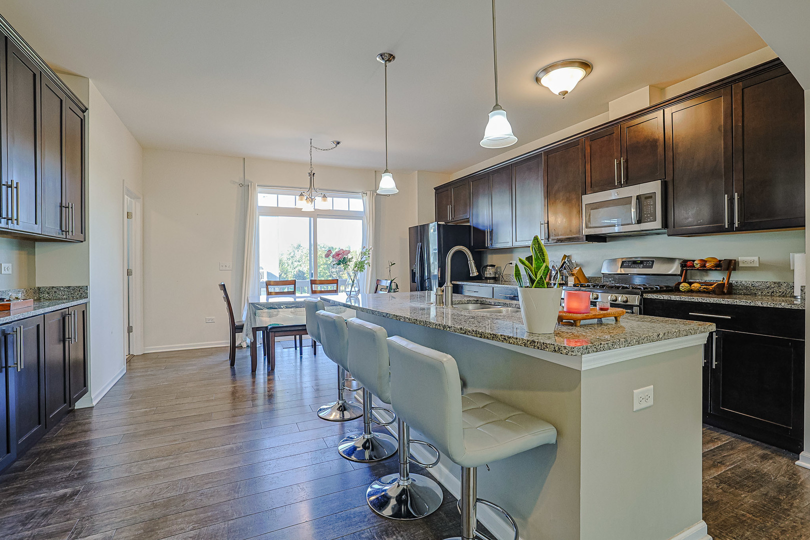299 Bennett Drive Carol Stream, IL 60188 - Photo 8 of 27 a kitchen with stainless steel appliances granite countertop a stove top oven a sink dishwasher a dining table and chairs with wooden floor