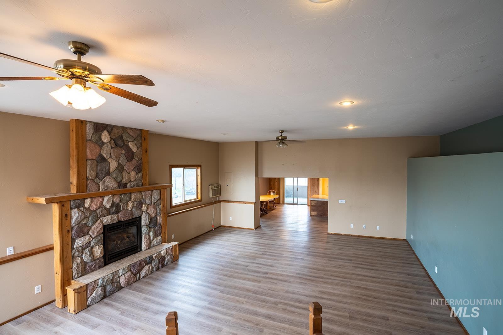 1357 Pound Lane Clarkston, WA 99403 - Photo 15 of 38 Unfurnished living room featuring ceiling fan, a stone fireplace, and wood finished floors