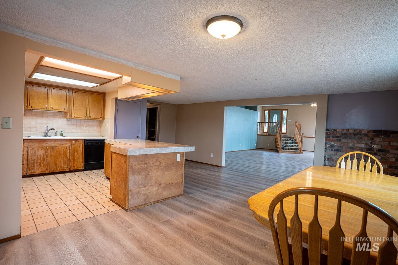 1357 Pound Lane Clarkston, WA 99403 - Photo 38 of 38 Kitchen featuring light countertops, a textured ceiling, light wood-style floors, black dishwasher, and open floor plan