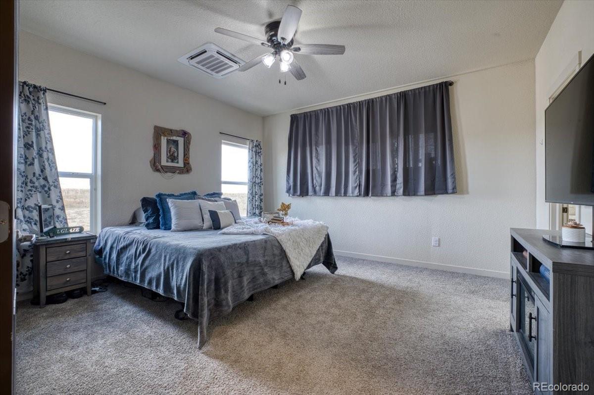 1215 North Yoder Road Yoder, CO 80864 - Photo 18 of 37 a spacious bedroom with a bed and a flat screen tv