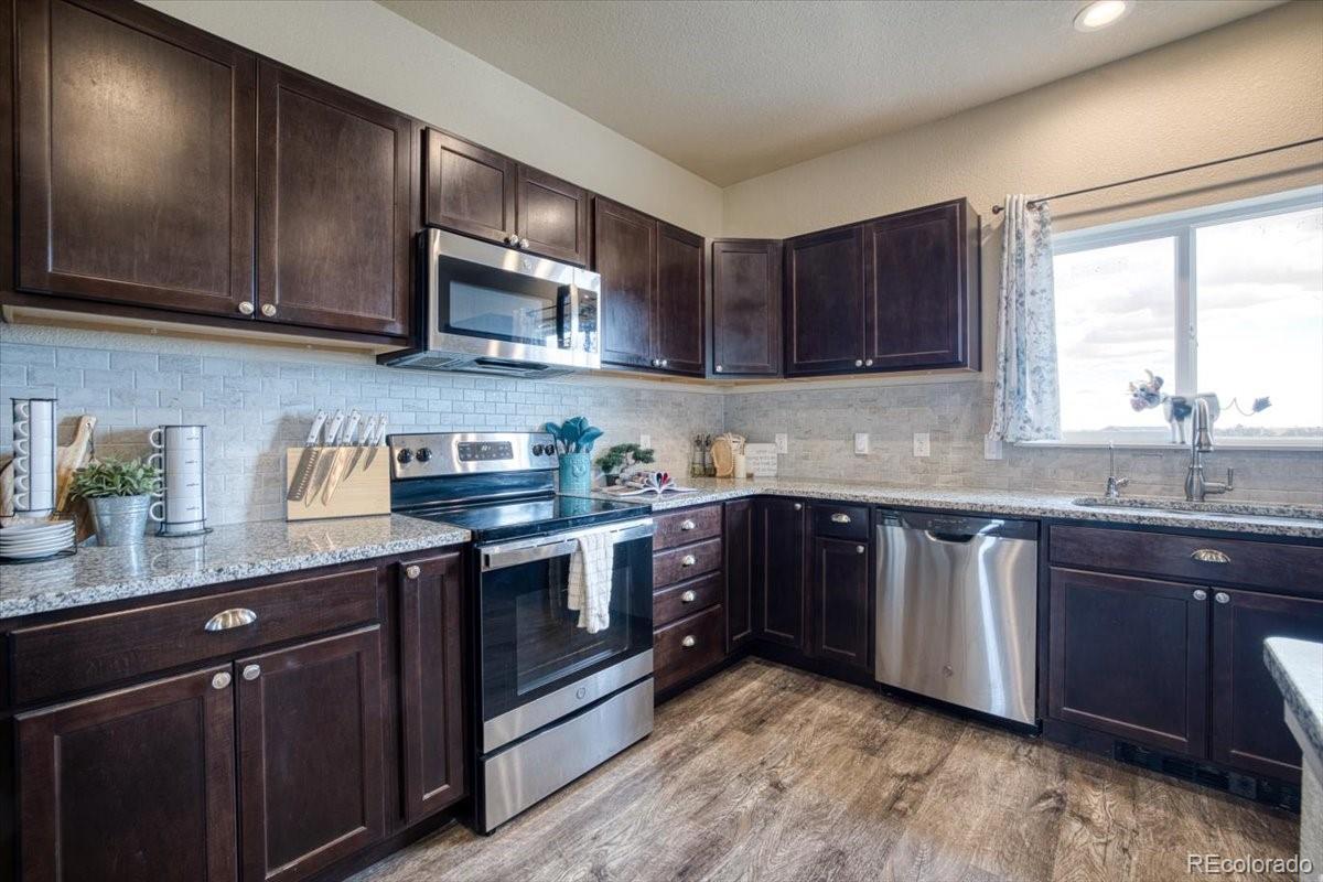 1215 North Yoder Road Yoder, CO 80864 - Photo 6 of 37 a kitchen with stainless steel appliances granite countertop wooden cabinets a sink and a stove