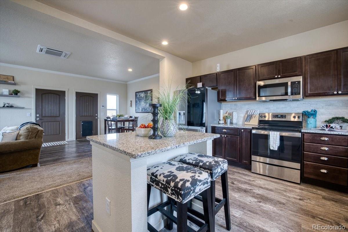 1215 North Yoder Road Yoder, CO 80864 - Photo 8 of 37 a kitchen with stainless steel appliances granite countertop a stove top oven a sink dishwasher a dining table and chairs with wooden floor