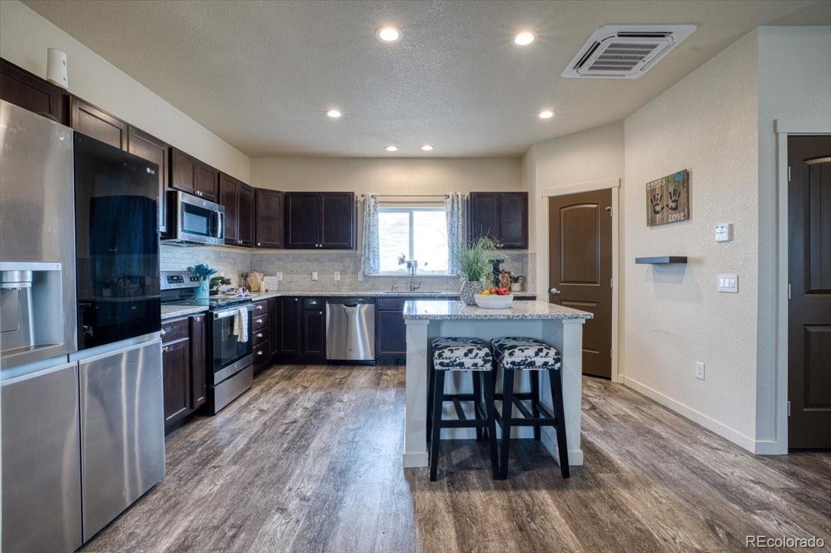 1215 North Yoder Road Yoder, CO 80864 - Photo 9 of 37 a kitchen with stainless steel appliances kitchen island granite countertop wooden floors and wooden cabinets