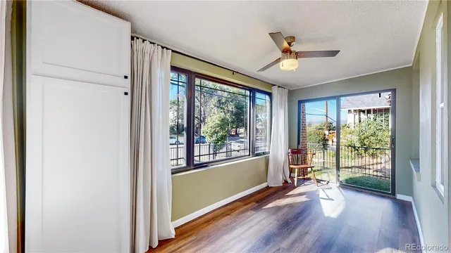 a view of a room with wooden floor ceiling fan and windows