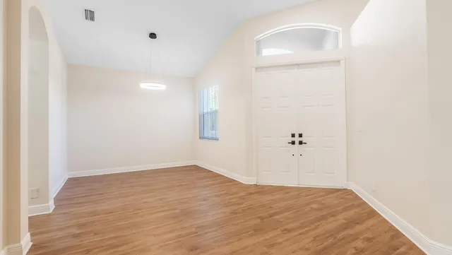 an empty room with wooden floor and mirror