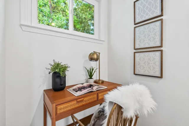 a view of a white house with a small yard and wooden fence