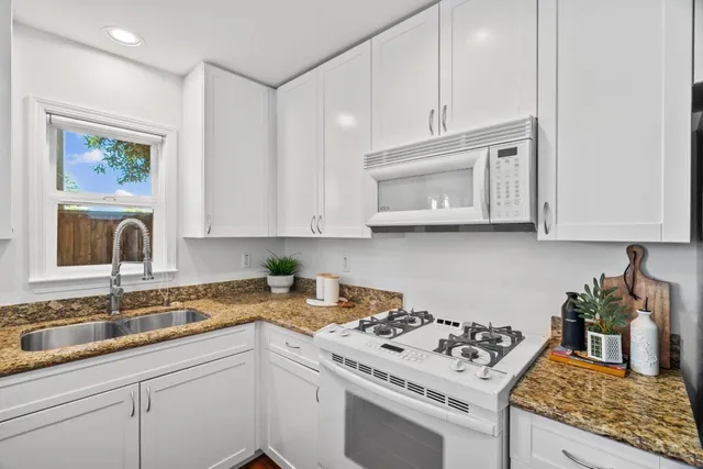 a kitchen with white cabinets and appliances