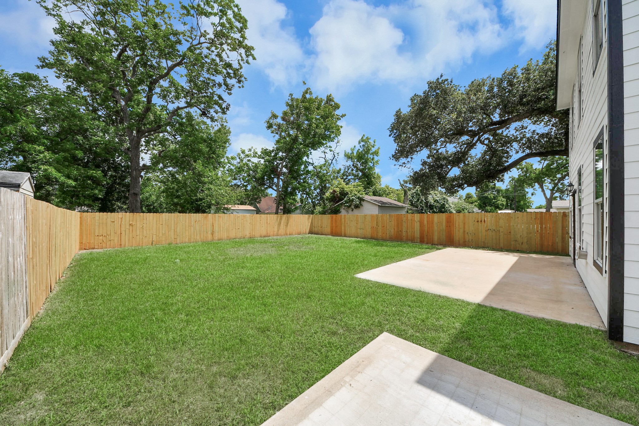 1105 East Kyle Road Clute, TX 77531 - Photo 39 of 44 Spacious backyard with two concrete patios, perfect for outdoor activities. The area is fenced for privacy and bordered by mature trees, offering a serene setting.