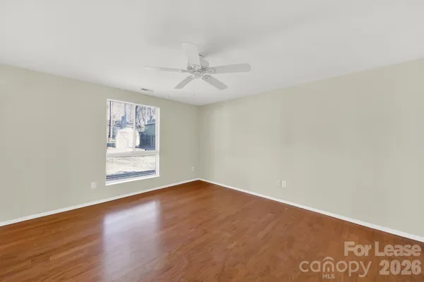 an empty room with wooden floor ceiling fan and windows