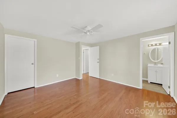 an empty room with wooden floor and a ceiling fan
