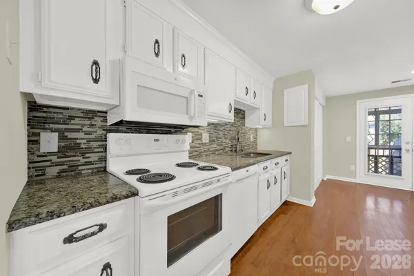 a kitchen with granite countertop white cabinets and white appliances