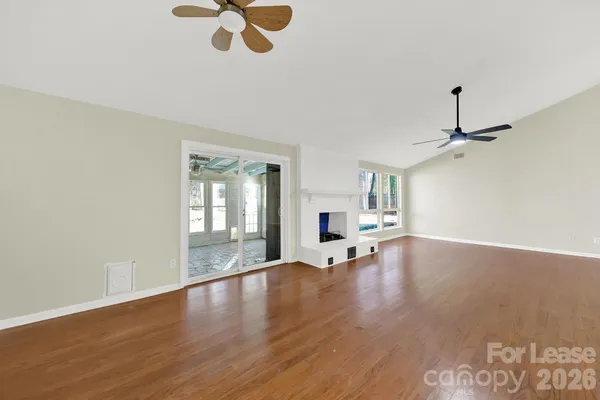a view of an empty room with window and wooden floor