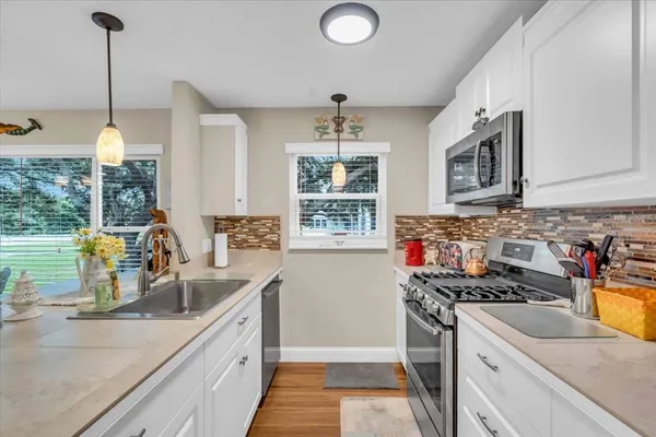 a kitchen with stainless steel appliances granite countertop a sink stove and cabinets