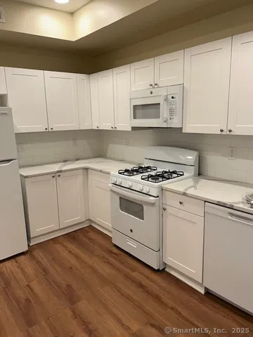 a kitchen with granite countertop white cabinets and white appliances