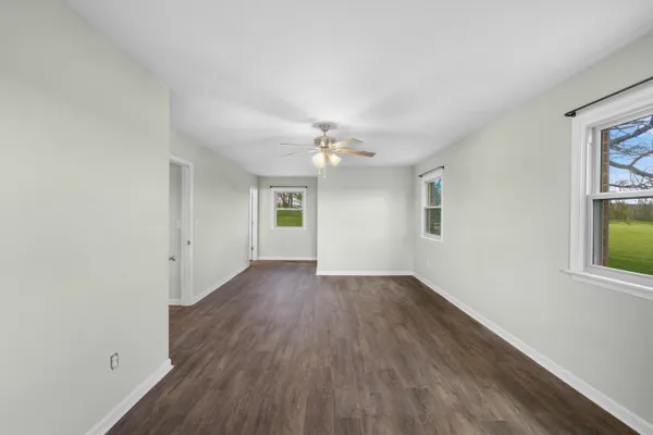 a view of an empty room with window and wooden floor