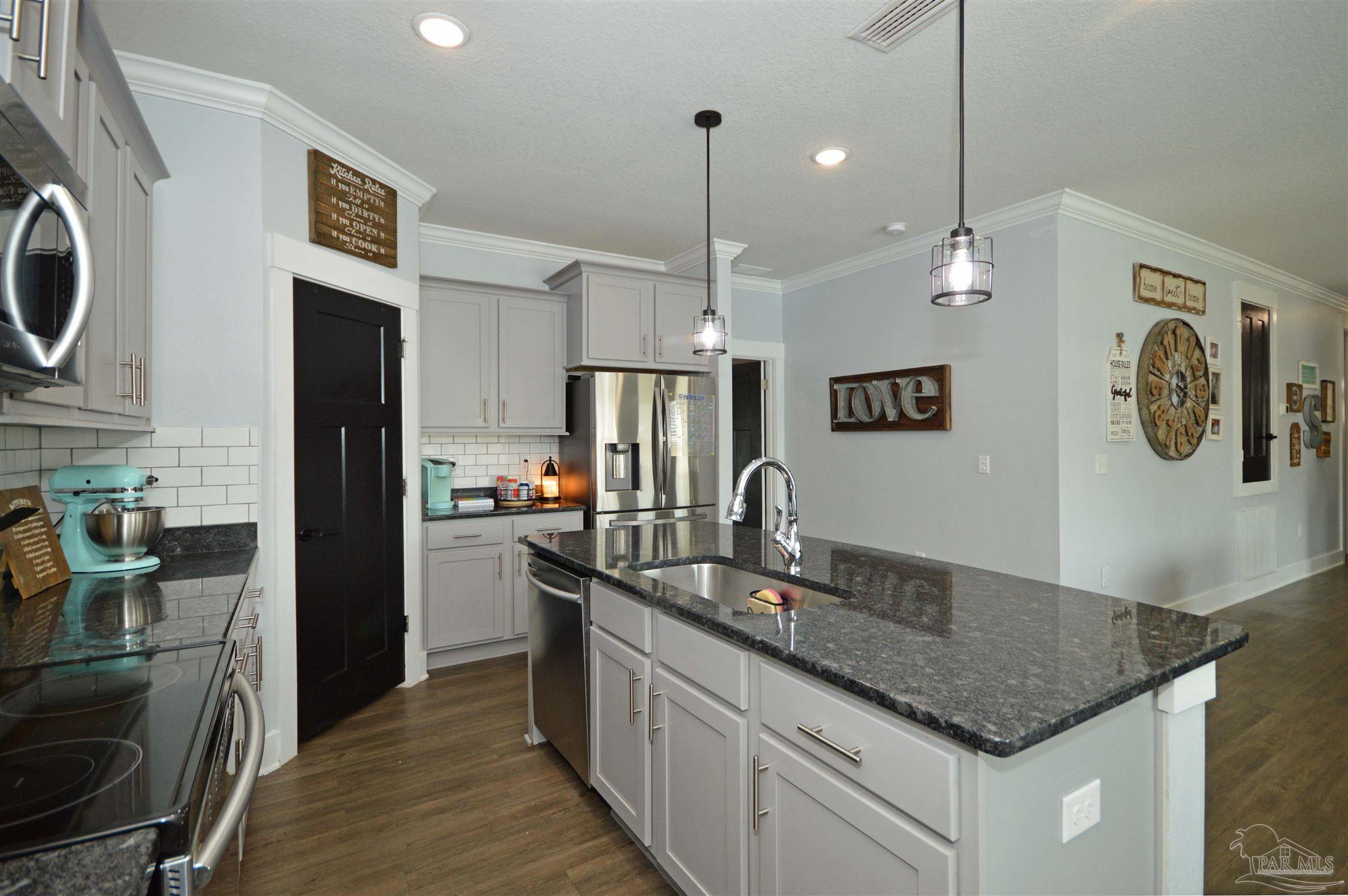 4453 Jude Way Pace, FL 32571 - Photo 18 of 41 a kitchen with kitchen island granite countertop a sink a counter space stainless steel appliances and cabinets