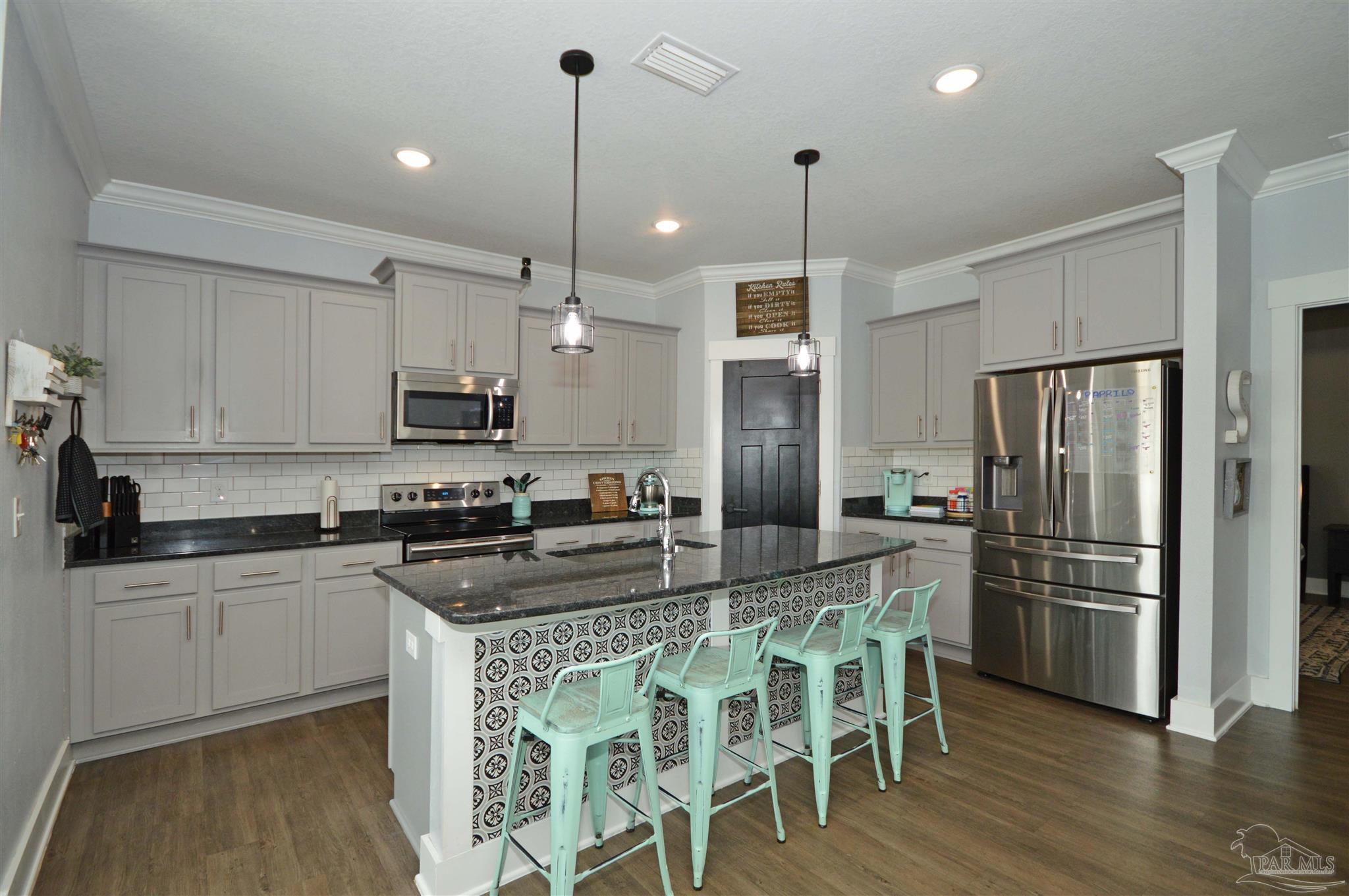 4453 Jude Way Pace, FL 32571 - Photo 19 of 41 a kitchen with stainless steel appliances granite countertop a stove a refrigerator a sink dishwasher a stove and white cabinets with wooden floor