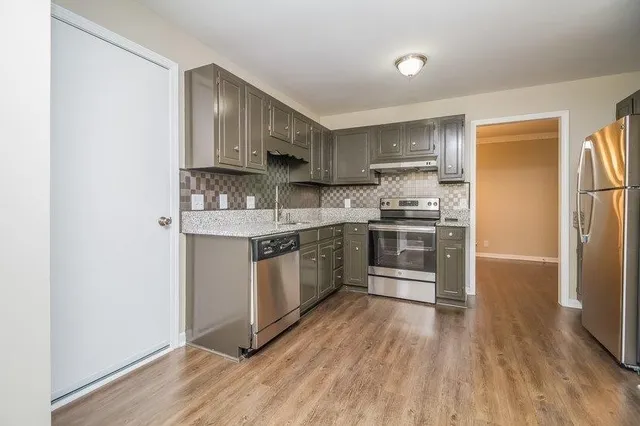 a kitchen with stainless steel appliances granite countertop a stove top oven a sink and a refrigerator